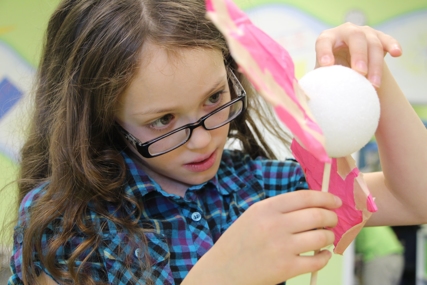 A girl focuses on building a project at a space camp.