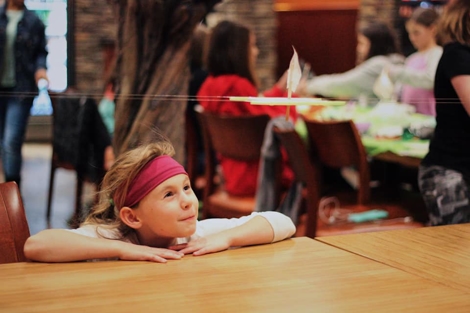 A girl at a table watches as a project is tested at a US space camp