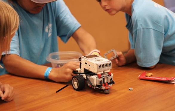 Three boys work on a robot at a STEM summer camp