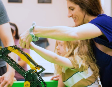 A parent and child work side by side to build a robot, sharing knowledge and enjoying a creative bonding moment. The project inspires curiosity and introduces engineering concepts in a supportive environment.